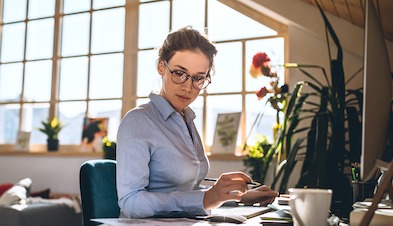 Woman working from home office with desktop and large window