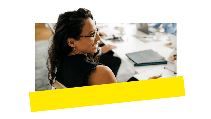 Een medewerker die met plezier meedoet aan een gesprek in een vergaderkamer.