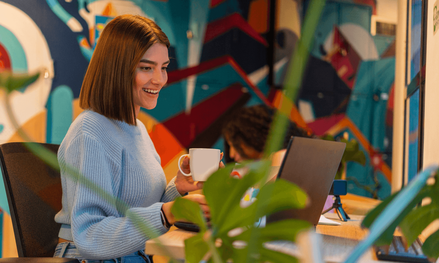 Mulher sorrindo e trabalhando em um notebook.